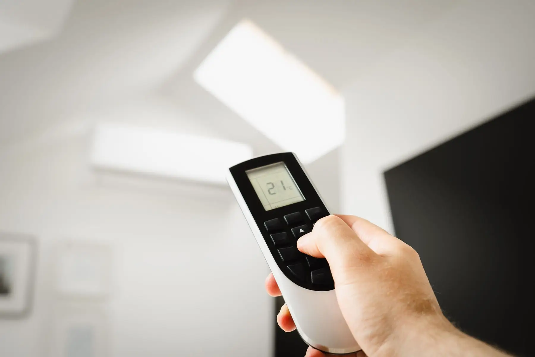 A hand setting a temperature on a split system remote